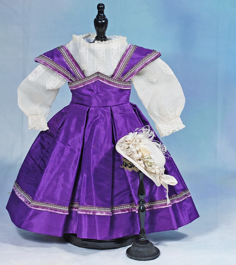PURPLE SILK TAFFETA GOWN WITH BONNET: Sized for 17”-18” poupee. Rich purple silk taffeta gown trimmed with bands of magenta silk chenille, box-pleated skirt, back hook-eye closing; plus dainty white cotton long-sleeve