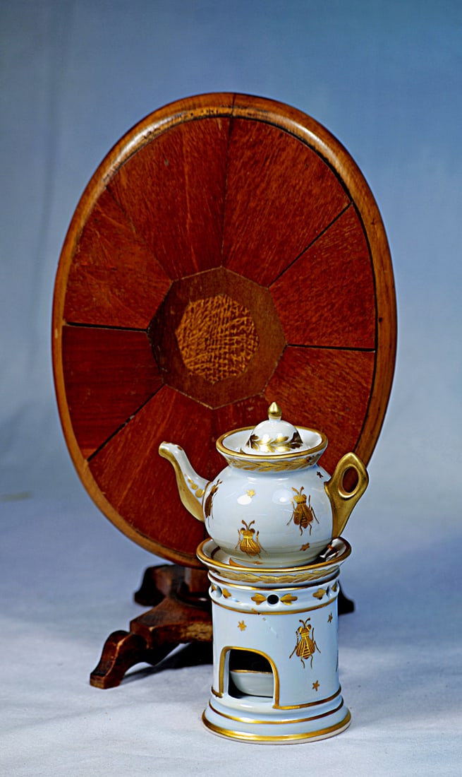 MINIATURE WOODEN TILT-TOP TABLE AND PORCELAIN TISANIERE: 6” H. Rosewood tilt-top pedestal table with maple wood inlay; along with a four-piece porcelain tisaniere with elaborate gilt decoration and edging, comprises tea pot, lid, pedestal stand