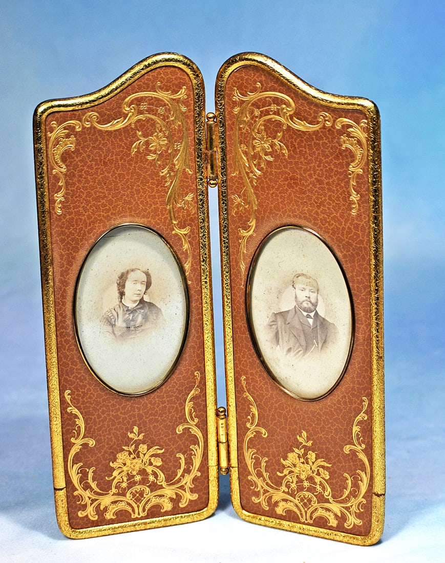 FRENCH FOLDING SCREEN WITH GILT EDGING AND TOOLED DESIGNS: 9 ½”. Firm-backed two panel hinged screen has tan kidskin cover with graceful gilt metal edging and rich tooled gilt designs; each panel has oval-shaped gilt frame with portrait of