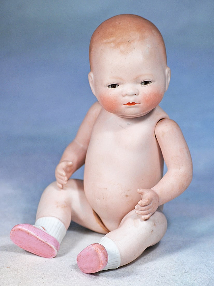 LARGE GERMAN ALL-BISQUE BYE-LO BABY WITH SWIVEL NECK AND GLASS EYES: 8 ½”. Marks: 6-20 copr. by Grace S. Putnam. Bisque swivel head on five-piece jointed bisque body, painted hair, brown glass sleep eyes, tinted brows, closed mouth, painted white socks
