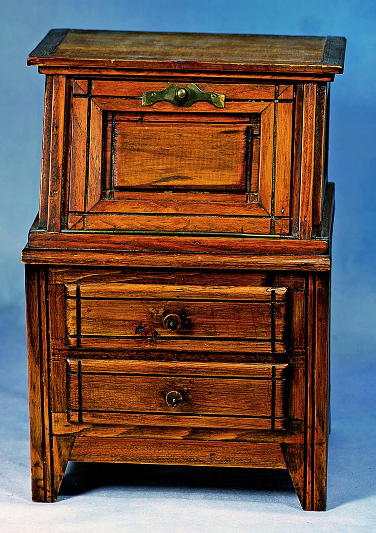 DOLL SIZE WOODEN SLANT-FRONT DESK: 11” H. x 7” W. Wooden slant-front desk opens to reveal an interior with one shelf and writing surface, brass latch; two drawers below with wooden pull knobs; tiny writing papers and