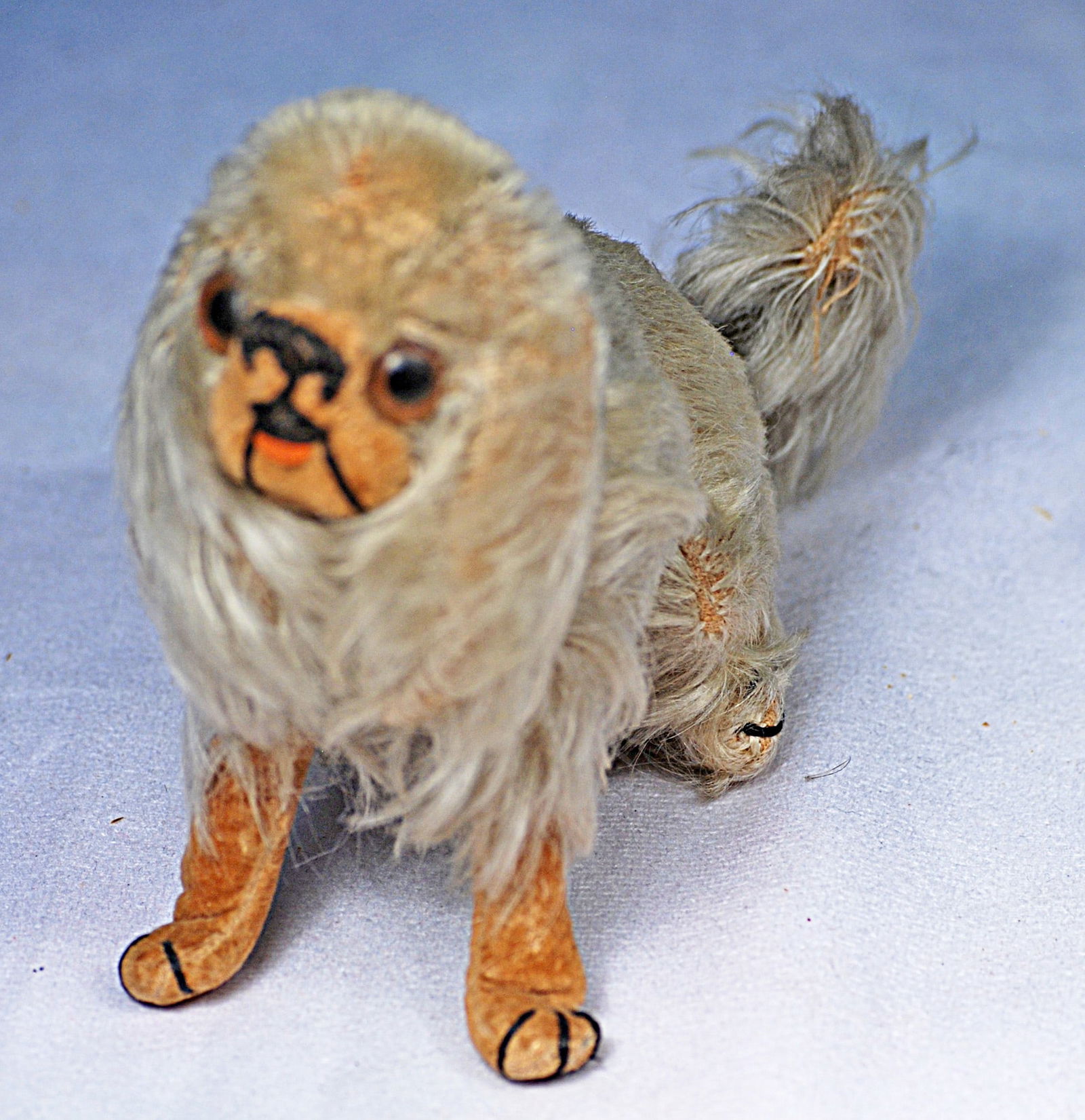 PEKINESE TOY DOG: 4 ½: H. Shaded long light gray fur over formed paper mache body, tan velvet face and feet, large round brown glass eyes, dark brown stitched nose, mouth and paws, fluffy tail, silk neck