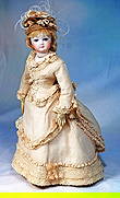 FRENCH BISQUE POUPEE IN ORIGINAL GOWN: 14”. Marks: None visible. Bisque swivel head on bisque shoulderplate, blue paperweight eyes, painted lashes, eyeliner, feathered brows, pierced ears, closed mouth, accented lips, blo
