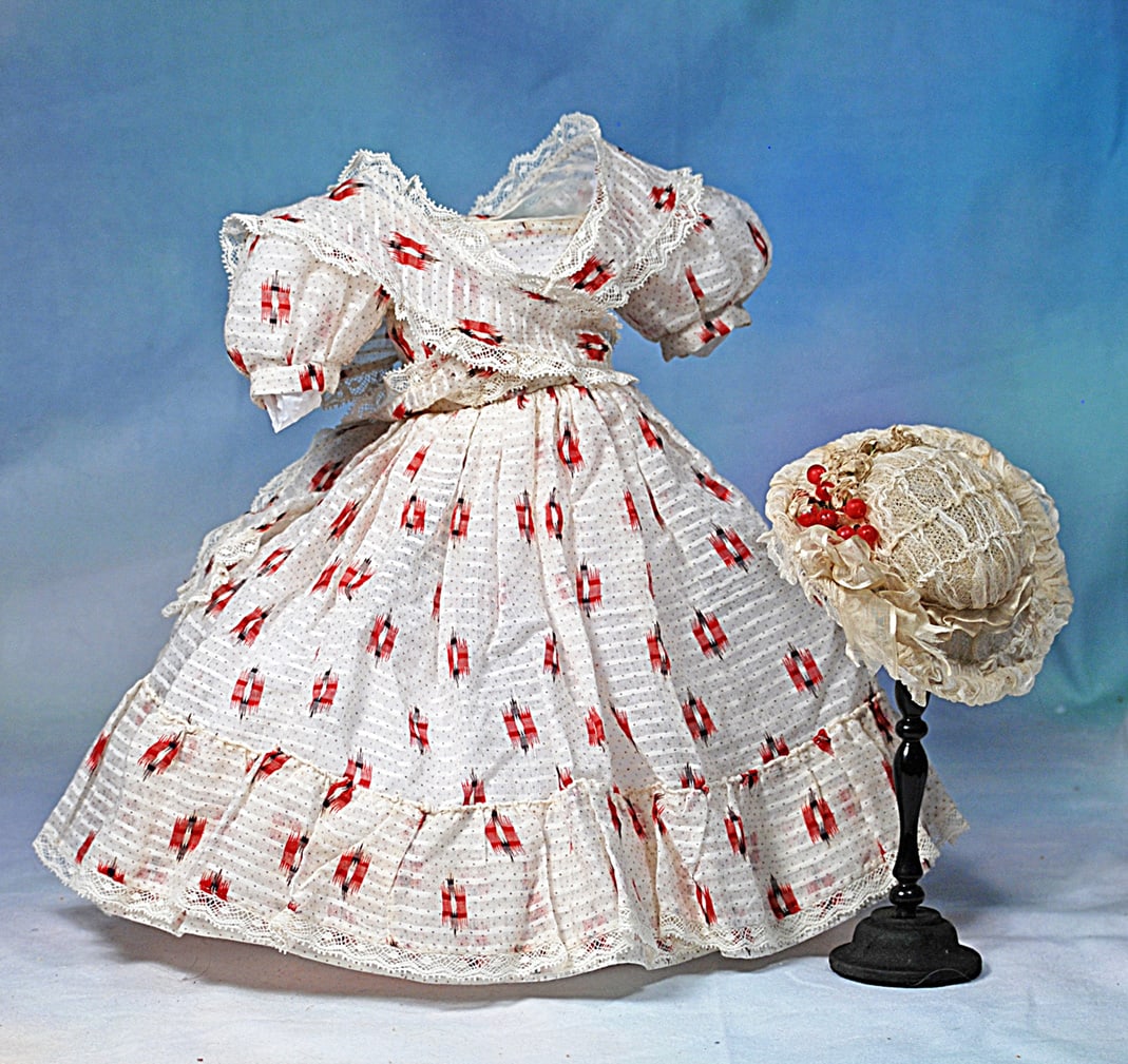 RED AND WHITE MUSLIN GOWN AND BONNET FOR POUPEE: Fine white and red printed muslin gown has rounded neckline, short puffed sleeves, full gathered skirt with ruffle, all trimmed in Valenciennes lace, with separate Marie Antoinette fichu; along with p