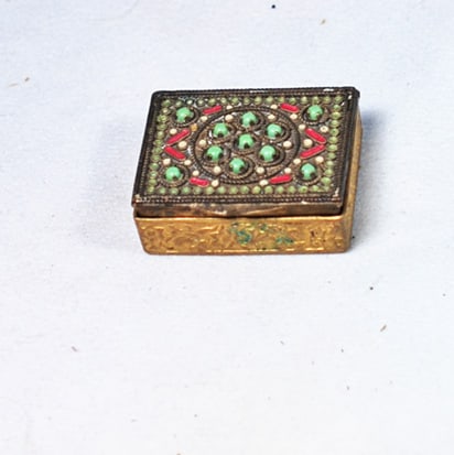 MINIATURE GILT METAL POWDER BOX: 1” x 1 ½”. Gilt-metal rectangular powder box with faux-jewel beads decorating the hinged top and with beveled mirror inside; contains a tiny powder puff with pink silk top.