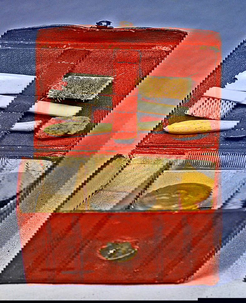 FRENCH, DARK RED LEATHER FITTED NECESSAIRE: 3” w. X 2” h. Rich dark red kidskin trunk with leather handle, brass closure, interior fitted with bone-handled brushes, silver powder box, comb, and sponge.