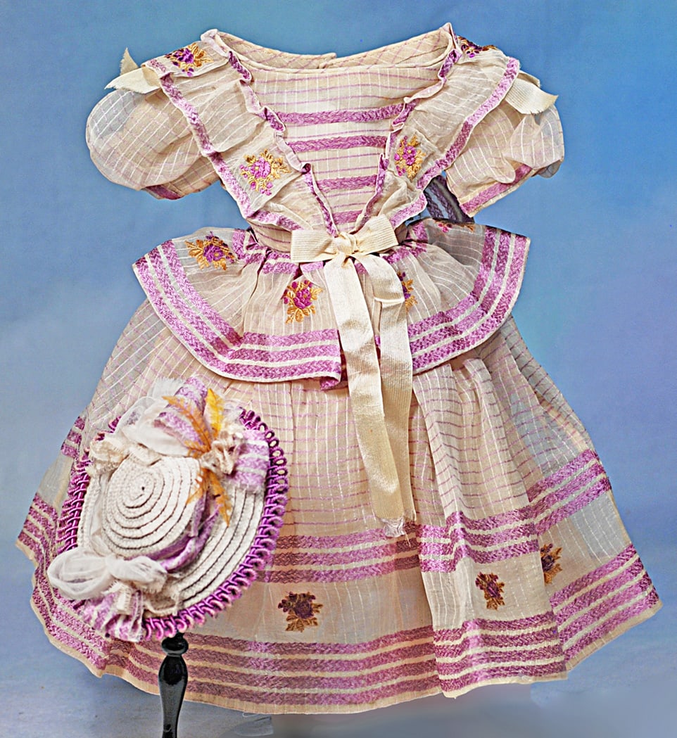 FINE COTTON GOWN FOR POUPEE WITH MAGENTA TRIM AND STRAW BONNET: Sheer muslin window-pain plaid gown in mode enfantine-style has pleated bretteles and basque at the back waist, gathered full skirt, generously accented with bands of magenta silk embroidery
