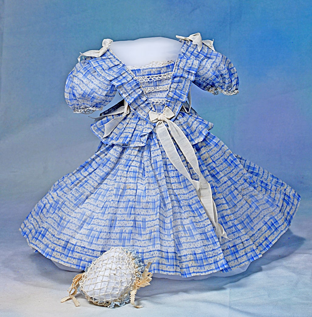 SHEER BLUE AND WHITE COTTON GOWN FOR POUPEE WITH HAND-KNITTED CAP: Airy white cotton with overlay of blue horizontal line and spots of flowers, further accented with white silk ribbons and bows, designed in mode enfantine style, has pleated bretteles and basque,