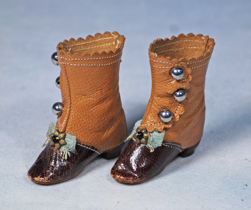 PAIR OF ANTIQUE DOLL BOOTS FOR POUPEE: 2”. Tan leather boots with rich brown leather uppers, three-button side closing, tiny aqua silk bows, wooden heels.