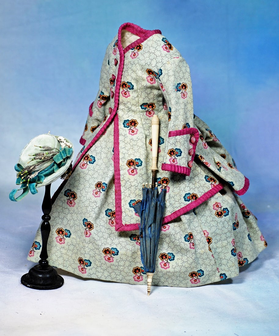 FINE GREEN WOOL GOWN AND ACCESSORIES FOR POUPEE: Pale green and pink woolen print bordered with crimped, magenta woolen braid, features a fitted jacket with deep cuffs and bustle back, brass buttons closing the front and accenting the cuffs and