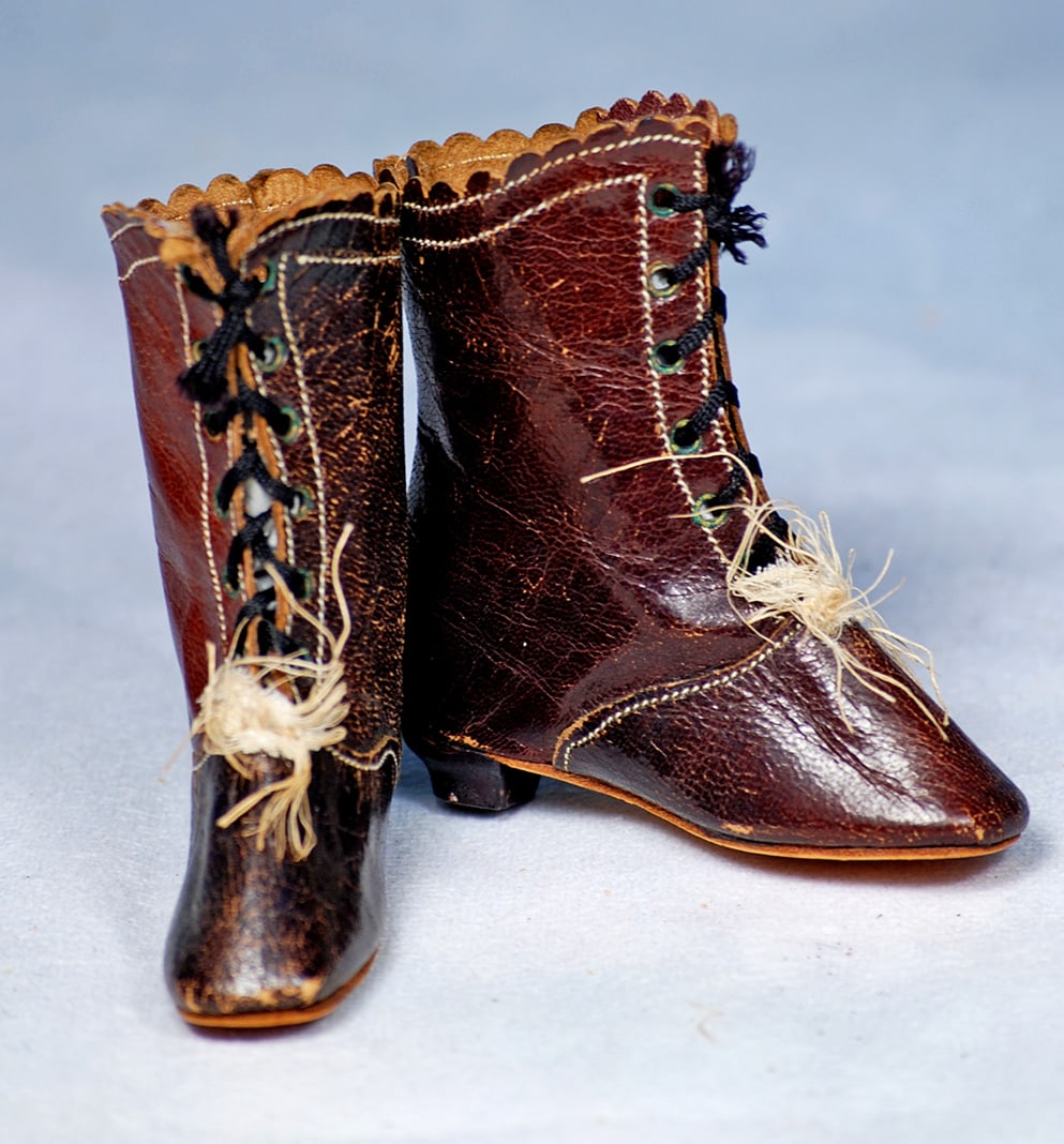 PAIR OF DARK LEATHER ANTIQUE DOLL BOOTS: Dark leather high-top books with scalloped edges, stitched accent detail front lacing, wooden heels.