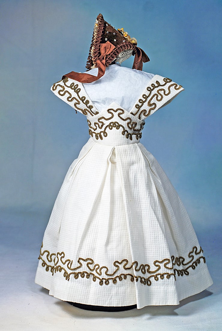 WHITE GOWN WITH DARK BROWN SOUTACHE TRIM FOR POUPEE: Fine white pique gown with high waist forming a bodice with wide straps, pleated skirt, richly embroidered all around with dark brown silk soutache, plus a wire-framed brown velvet bonnet with velvet