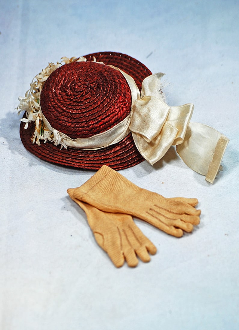 DOLL BONNET AND PAIR OF GLOVES: Burgundy straw bonnet with firmly shaped crown and brim accented with spray and white flowers, silk ribbon and bow with streamers, for about 6"-7” head circumference; along with pair of 3”