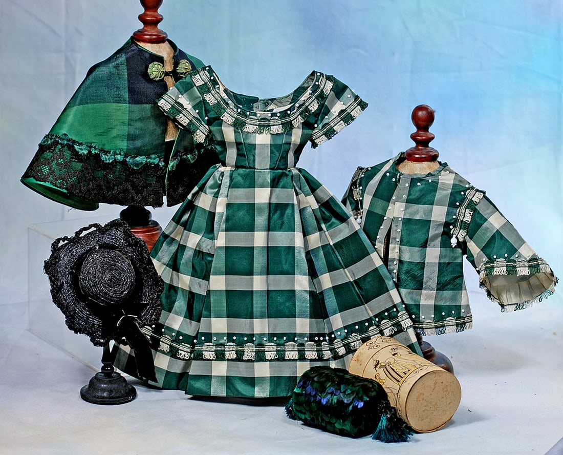 GREEN AND WHITE SILK ENSEMBLE FOR POUPEE: Comprising a emerald green and white silk plaid gown with fitted bodice having rounded neckline, short flared sleeves, constructed and box-pleated skirt, all trimmed in stylish fringe and tiny opaque