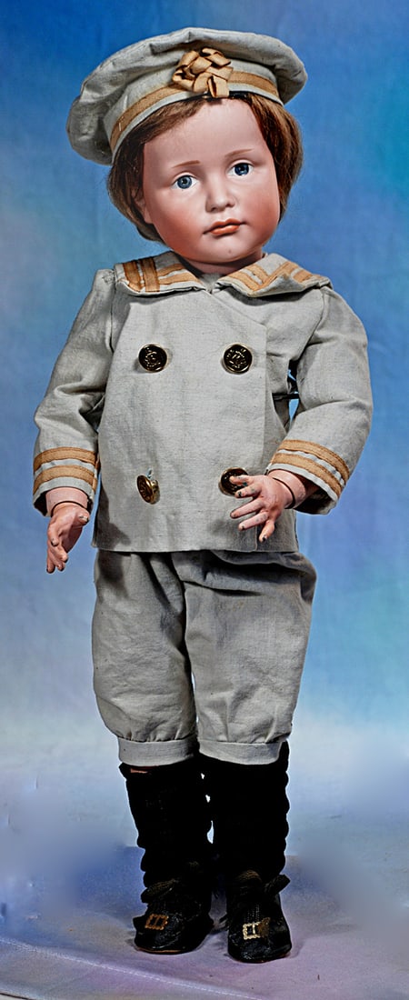 LARGE MODEL OF GERMAN BISQUE ART CHARACTER, 114, BY KAMMER AND REINHARDT: 19”. Marks: K * R 114. Bisque socket head, painted features, blue eyes, upper eyeliner, tapered brows, closed mouth, accented and shaded lips in pouty expression, antique brown mohai