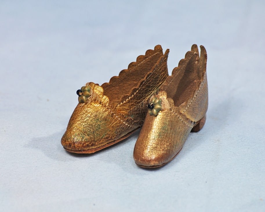 PAIR OF FRENCH KIDSKIN SHOES FOR POUPEE: 2”. Narrow-shaped kidskin shoes with rich gilt finish and star center decoration, wooden heels.