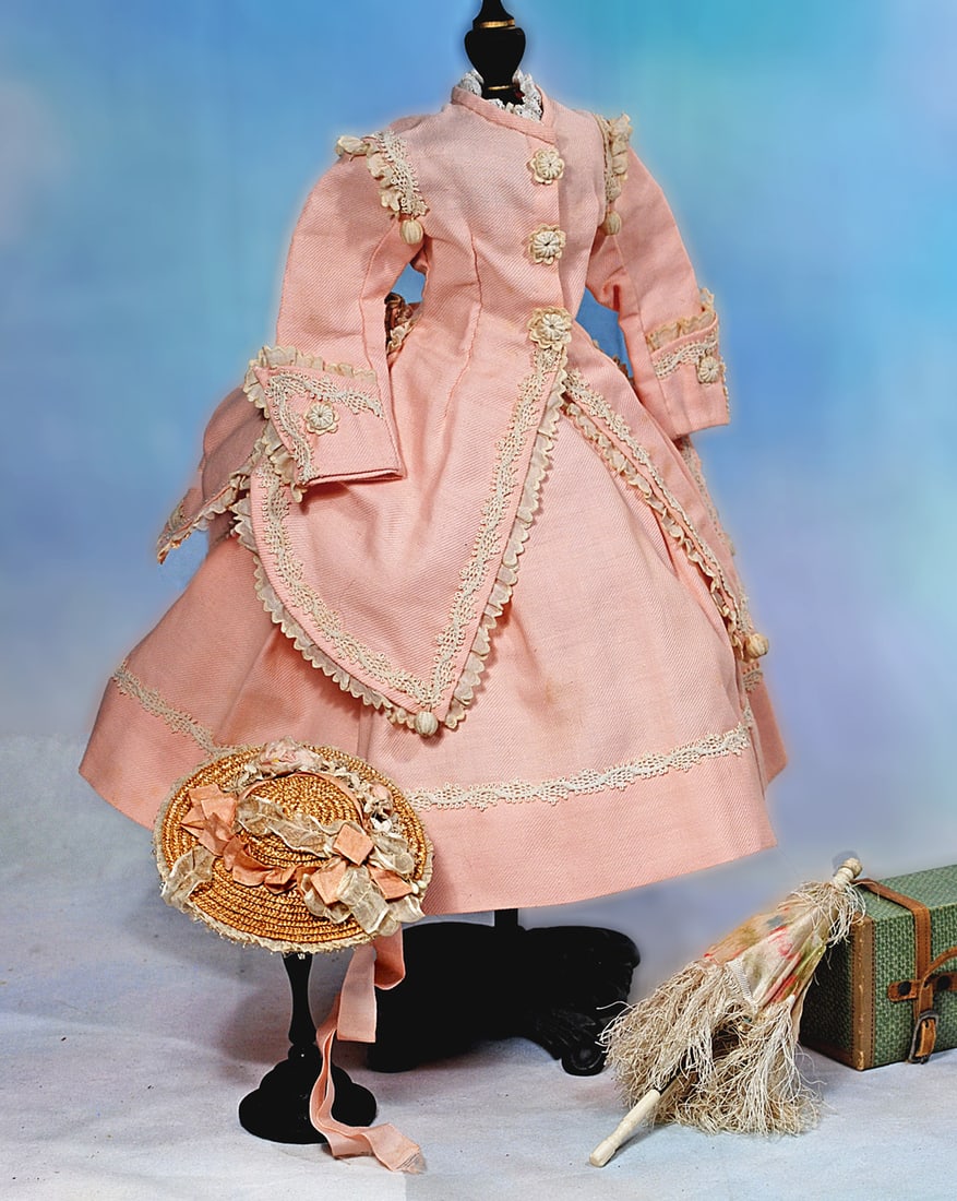 PINK COTTON PIQUE ENSEMBLE FOR POUPEE: Comprising a gown with fitted jacket with long tapered front panels, long sleeves, rounded basque at the back waist, pleated skirt; richly trimmed all round with scalloped edging and fanciful braid al