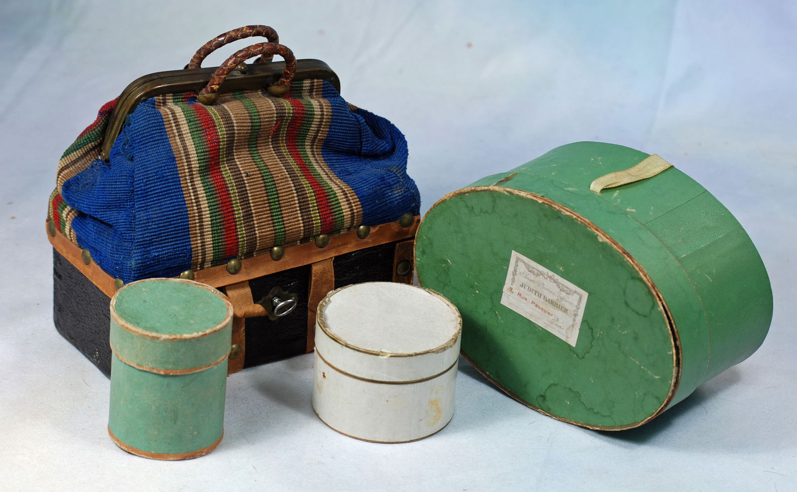 THREE FRENCH HAT BOXES AND SAC DU VOAGE: Three cardboard hatboxes, 2” to 3”, with paper covering, one with original shop label; plus a contemporary two compartment valise with wooden and canvas cover, leather handles.