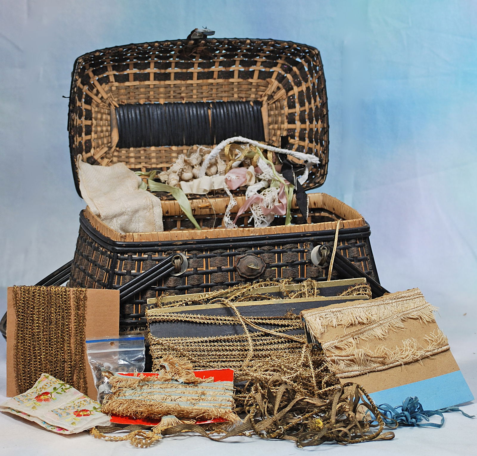FRENCH WICKER TRAVEL CASE FILLED WITH TRIMS FOR COSTUMING DOLLS: 16” x 12” case containing many items for sewing doll costumes.