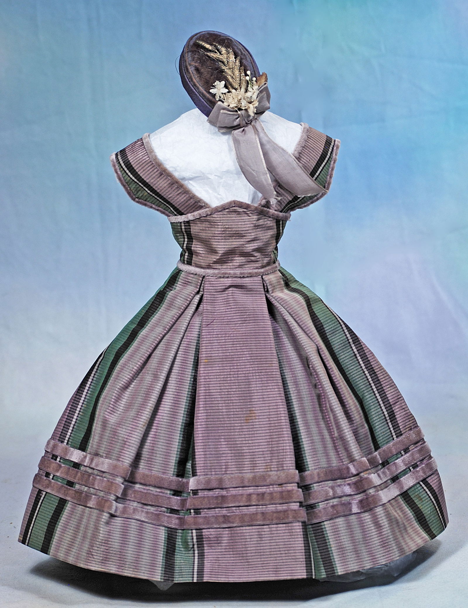LAVENDER SILK GOWN AND VELVET BONNET FOR POUPEE: Comprising a fine lavender, green and purple patterned silk high-waist gown that forms a bodice with wide straps, constructed waist, and box-pleated skirt, all trimmed in rich lavender velvet, plus a