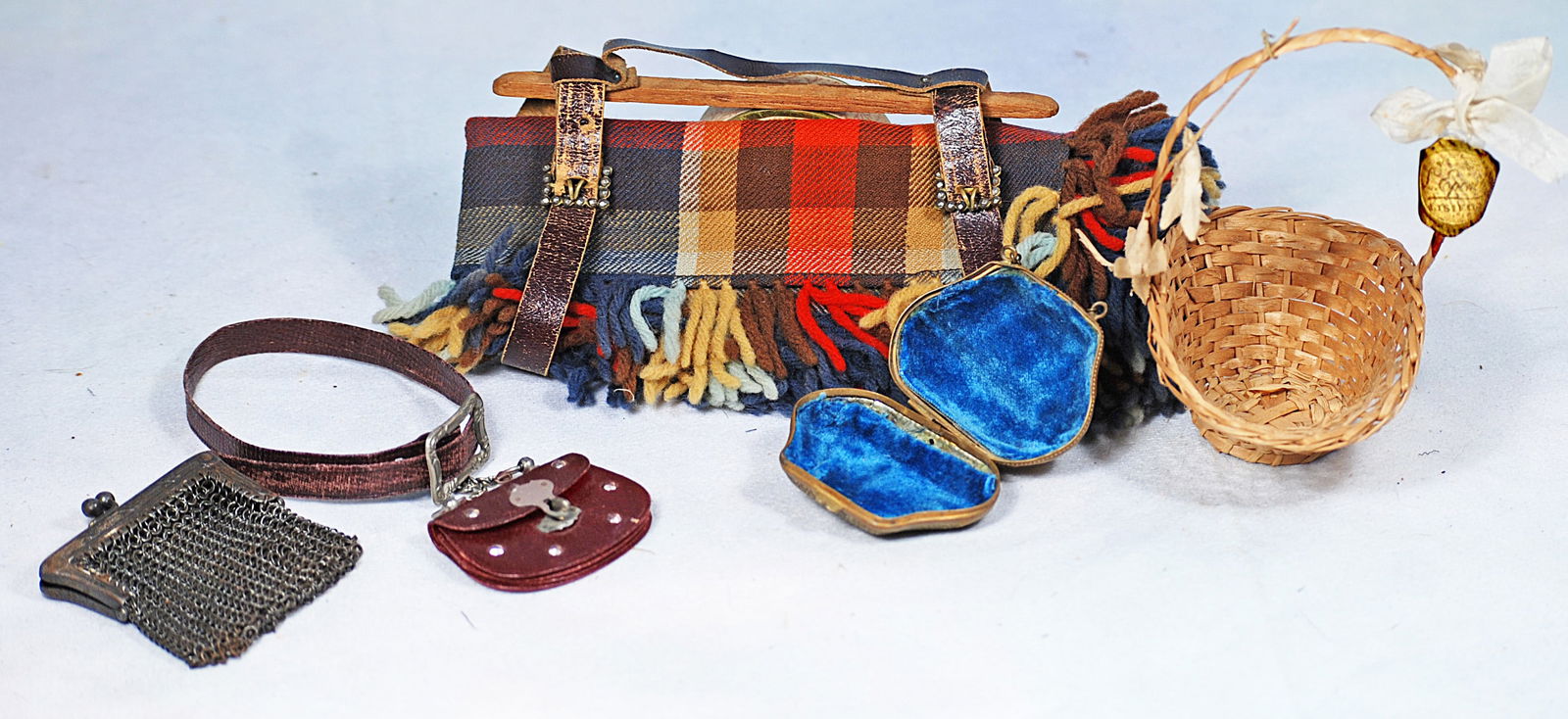 ACCESSORIES FOR POUPEE.: 243. ACCESSORIES FOR POUPEE. Includes 6” wool plaid blanker wrap with leather straps, dark maroon leather purse with matching belt; metal mesh purse, gilt metal purse with teal velvet lining,