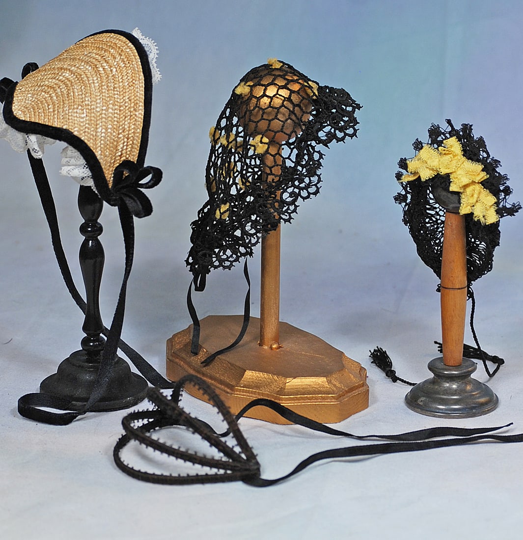 FOUR BONNETS.: 258. FOUR BONNETS. Including a woven straw bonnet with black velvet trim and white ruffled lace edging; black and yellow hand-tied cap black silk ties; black hand-tied cap with cluster of yellow