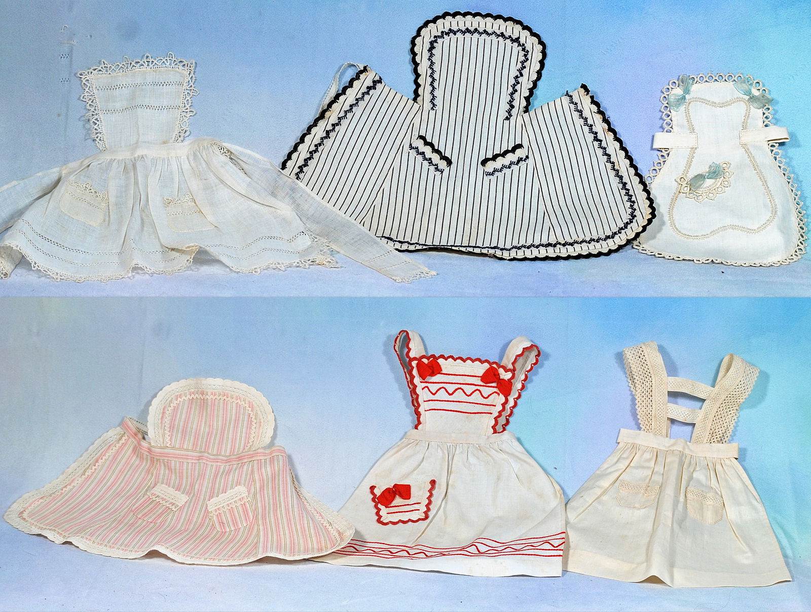 COLLECTION OF SIX APRONS FOR LADY DOLL OR POUPEE.: 259. COLLECTION OF SIX APRONS FOR LADY DOLL OR POUPEE. 6 ½” to 10 ½” sizes. Assorted styles of cotton aprons with various detail and trimming, for approximately 17”