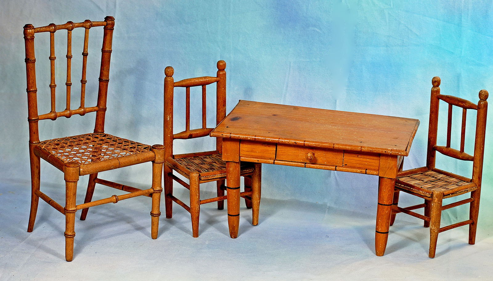 ANTIQUE MAPLE WOOD DOLL SIZE FURNISHINGS.: 264. ANTIQUE MAPLE WOOD DOLL SIZE FURNISHINGS. Comprising a maple wood table, 6 ½” x 10 ½”, two chairs with woven reed seat; 12” French chair with faux-bamboo