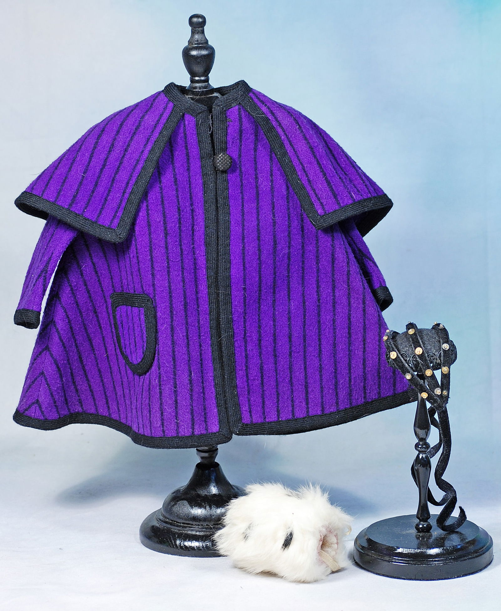 PURPLE WOOL CAPE, CORONET AND FEATHER MUFF: 295-A. PURPLE WOOL CAPE, CORONET AND FEATHER MUFF. Rich purple wool striped cape with collar, long sleeves, front pocket, edged all around with black wool felt trim, 10 ½” front