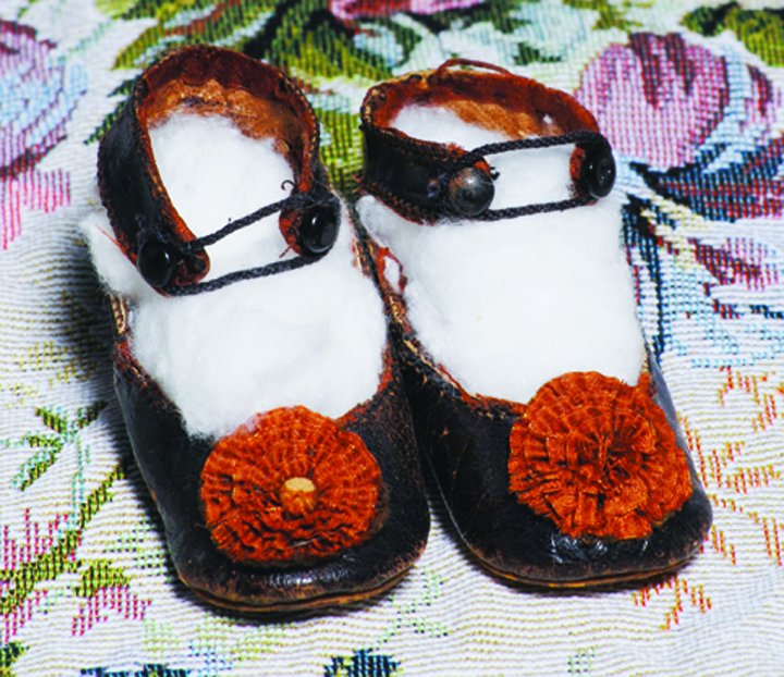 PAIR OF BROWN LEATHER SHOES WITH SILK ROSETTES. Marks:: PAIR OF BROWN LEATHER SHOES WITH SILK ROSETTES. Marks: C.M. in oval. 3” L. Dark brown leather shoes have ankle strap closing, brown silk rosettes, leather soles. Commentary: Antique factory shoes, m