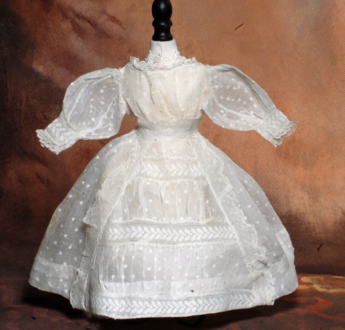 ANTIQUE WHITE DOTTED SWISS FASHION DRESS.: 289. ANTIQUE WHITE DOTTED SWISS FASHION DRESS. 4 ¼” shoulder width, 11” length. Semi-sheer dotted swiss with gathered bodice, rounded neckline poufed sleeves with fit bands, lace edging at neck a