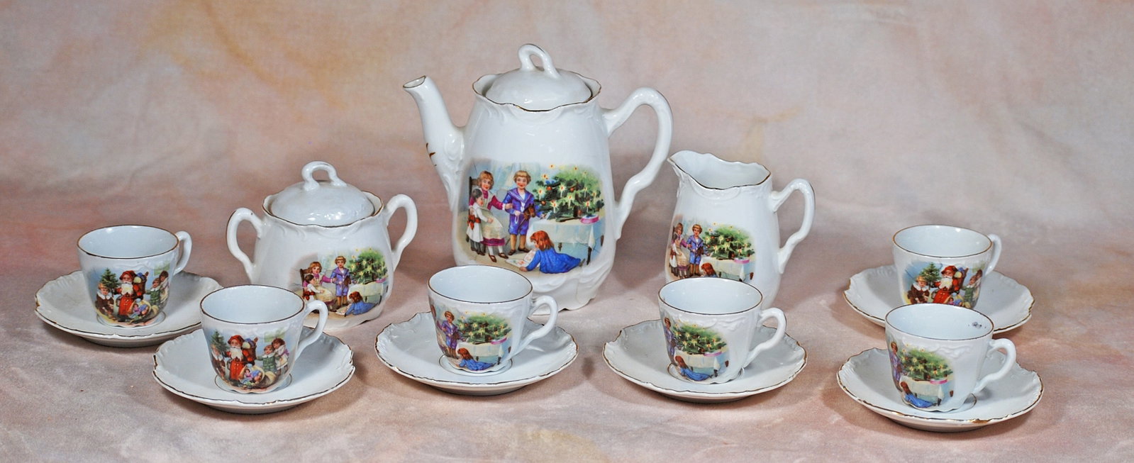 GERMAN PORCELAIN CHILD SIZE TEA SERVICE.: GERMAN PORCELAIN CHILD SIZE TEA SERVICE. Fine white porcelain with gilt accents and having Victorian-era scenes of children gathered round a Christmas scene. Comprising lidded teapot (8”), lidde