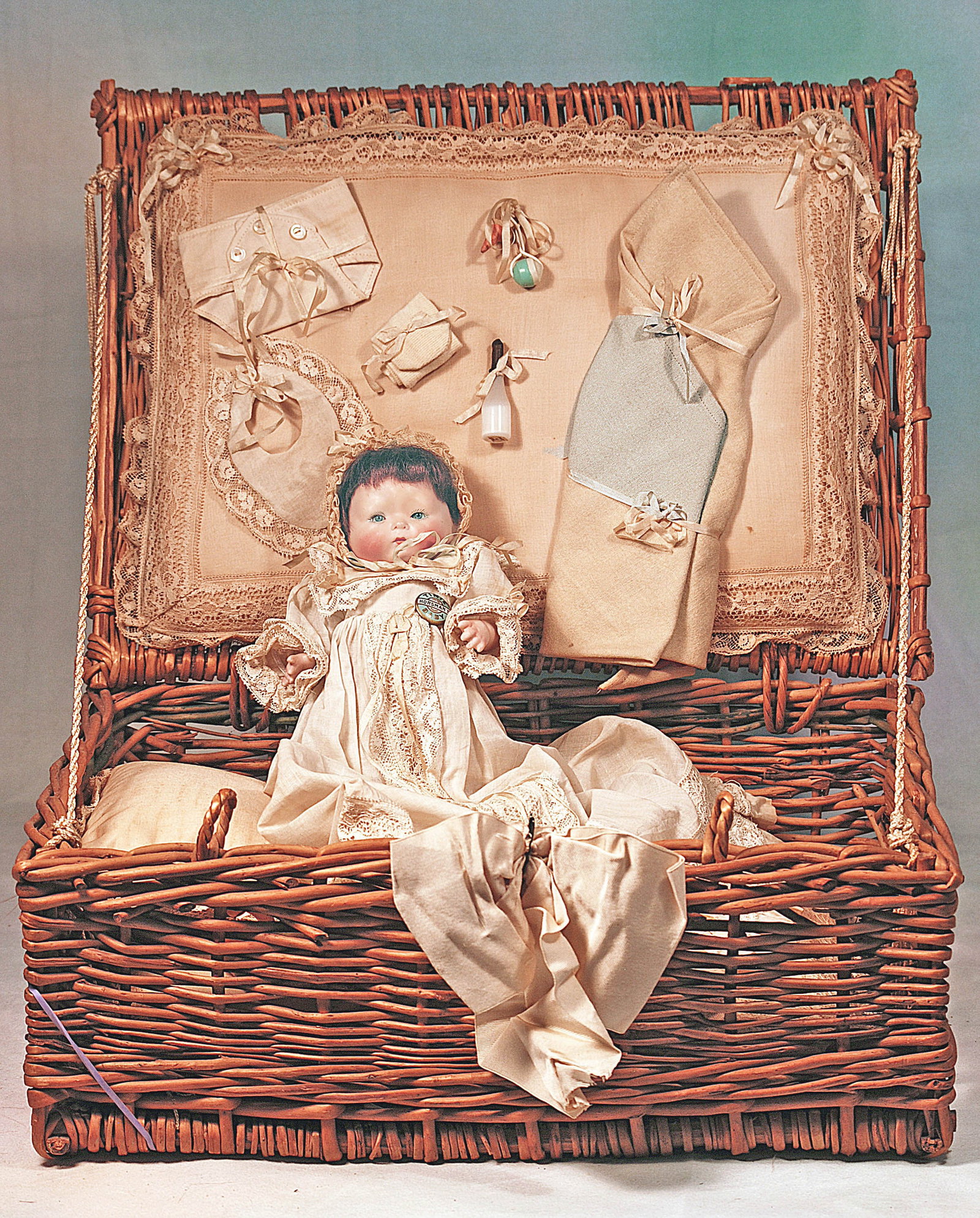 GERGEMAN, RARE LARGE SIZE, ALL-BISQUE TYNIE BABY BY HORSMAN IN WICKER LAYETTE.: 24. GERMAN, RARE LARGE SIZE, ALL-BISQUE TYNIE BABY BY HORSMAN IN WICKER LAYETTE. 8”. Marks: c. 1924 by E.I. Horsman Co. Bisque swivel head of young baby on all-bisque jointed baby body, blue
