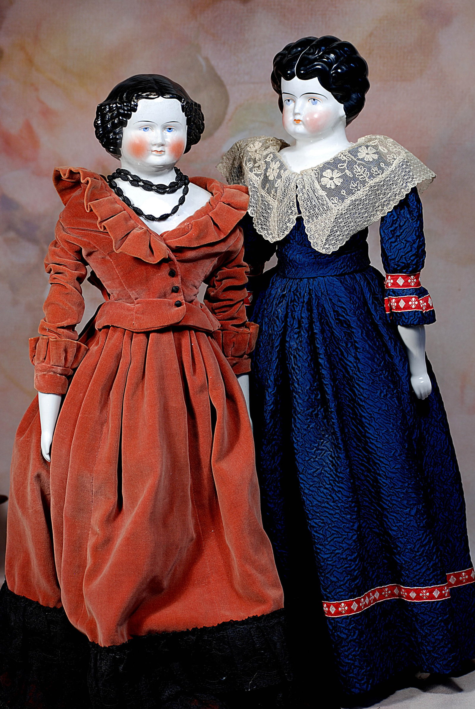 TWO GERMAN PORCELAIN LADIES.: 81. TWO GERMAN PORCELAIN LADIES. 25”. Each has porcelain shoulderhead with sculpted black hair, painted features, blue eyes, eyeliner and tapered brows, closed mouth, cloth stitch-jointed body