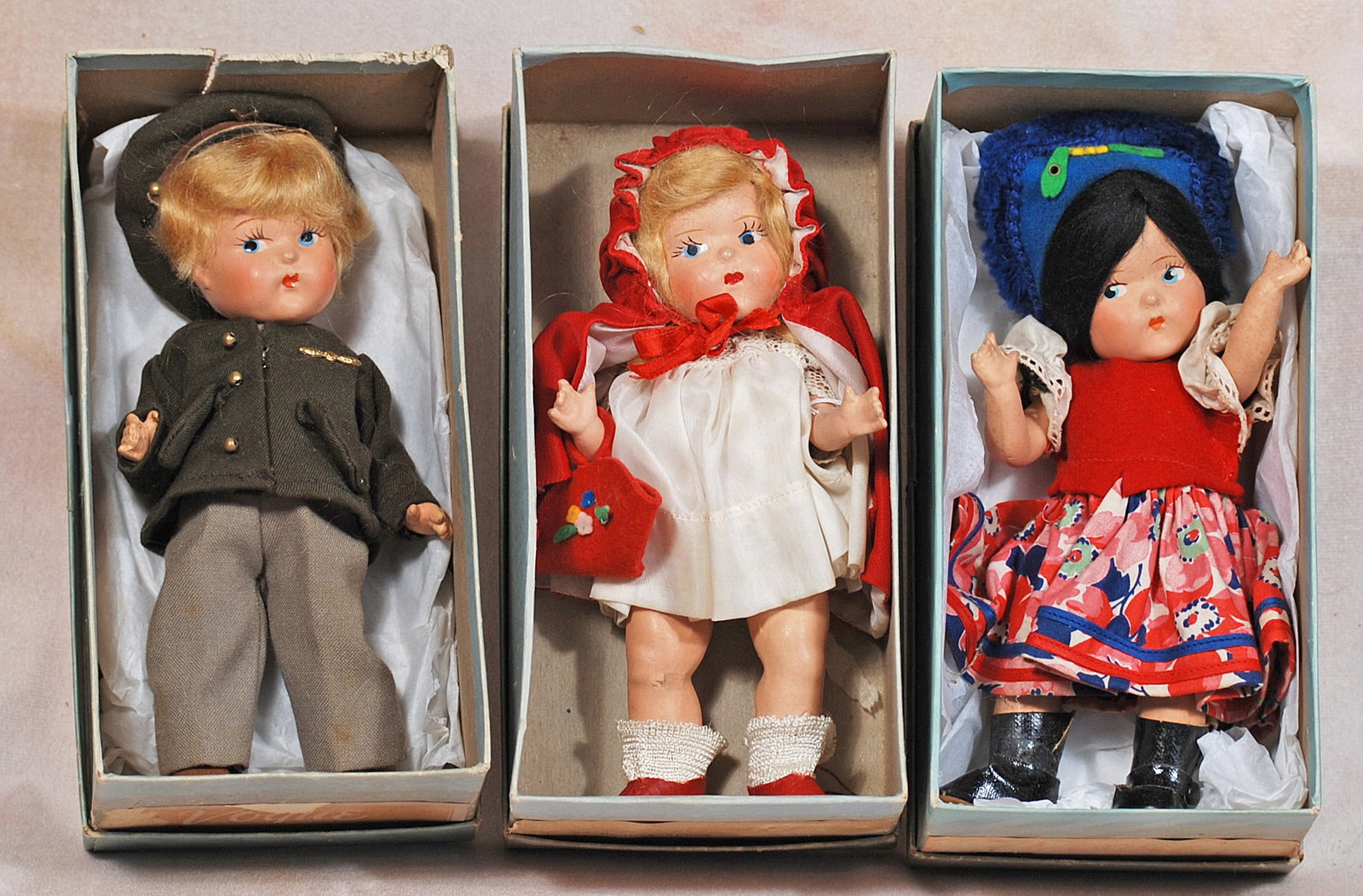 THREE EARLY COMPOSITION VOGUE GINNY DOLLS IN ORIGINAL BOXES.: 92. THREE EARLY COMPOSITION VOGUE GINNY DOLLS IN ORIGINAL BOXES. 7”. Composition dolls, socket head, five-piece jointed body, painted features, mohair wig, original costumes, one as “Russian