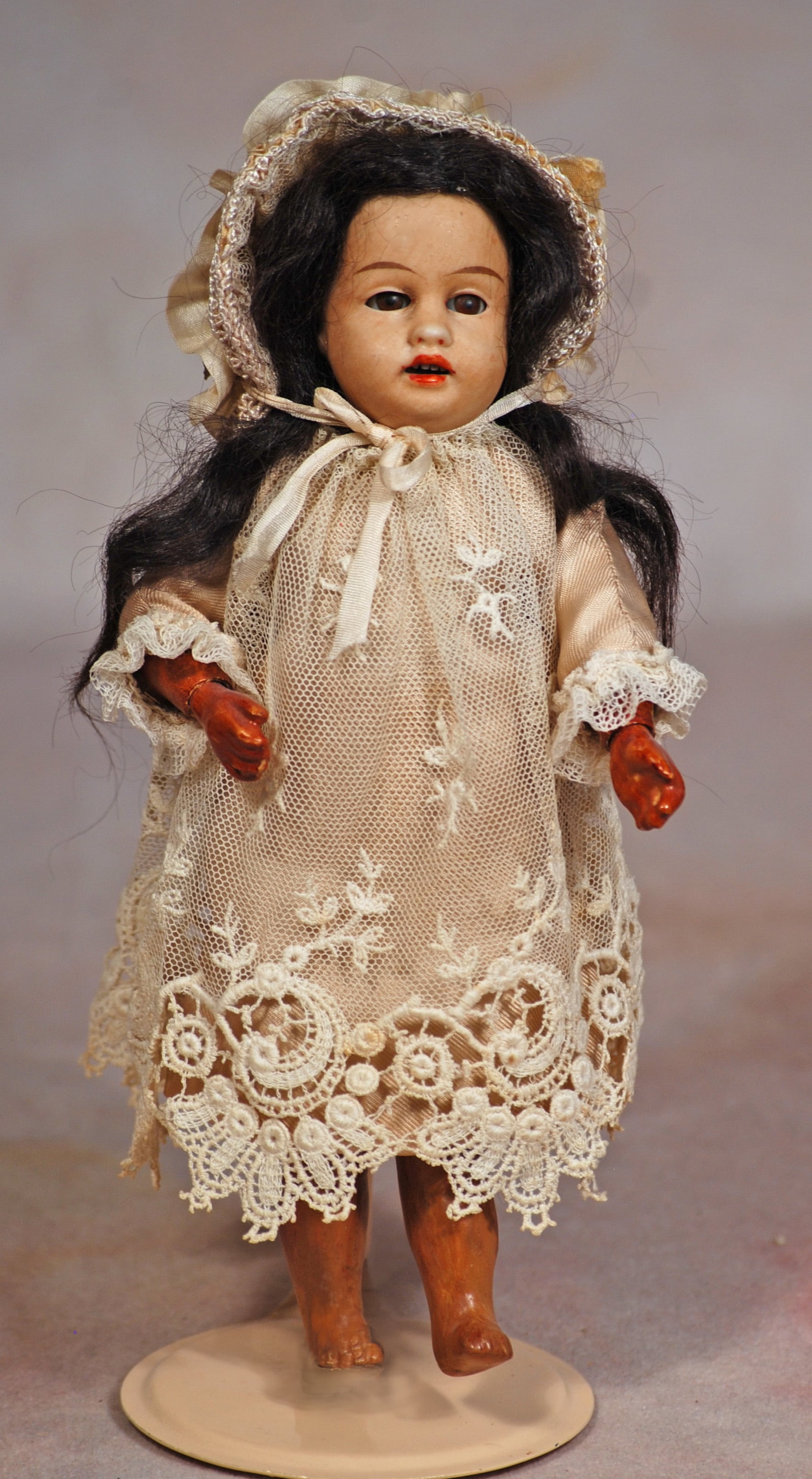 PETITE BROWN BISQUE DOLL BY GEBRUDER KUHNLENZ: 97. PETITE BROWN BISQUE DOLL BY GEBRUDER KUHNLENZ. 7 ½”. Marks: 34 over 17. Light brown bisque socket head, brown sleep eyes, tapered brows, open mouth, upper teeth, black mohair wig,
