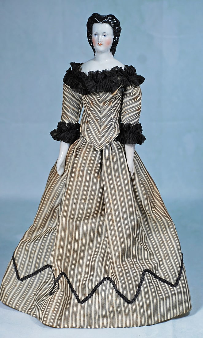 GERMAN PORCELAIN LADY WITH ELABORATELY SCULPTED COIFFURE: 16”. Porcelain shoulderhead, sculpted black hair, center-parted and waved away from face with extensive brush marked detail framing the face, high curls at the front with detailed ringlet curls 