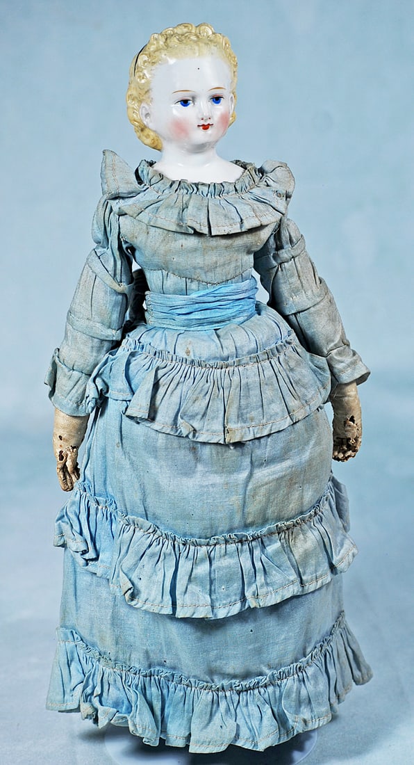 GERMAN PORCELAIN LADY DOLL WITH BEAUTIFUL EYES: 15”. Porcelain shoulderhead with sculpted blonde hair in deeply defined curls, waved away from her face and behind sculpted ears, curls at the back and narrow black head band, painted large blue