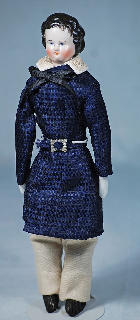 GERMAN PORCELAIN YOUNG BOY: 11 ½”. Porcelain shoulderhead depicting young boy with sculpted and side-parted black wavy hair with brush-marked detail, painted blue eyes, black eyeliner, tapered brows, closed mouth, mus