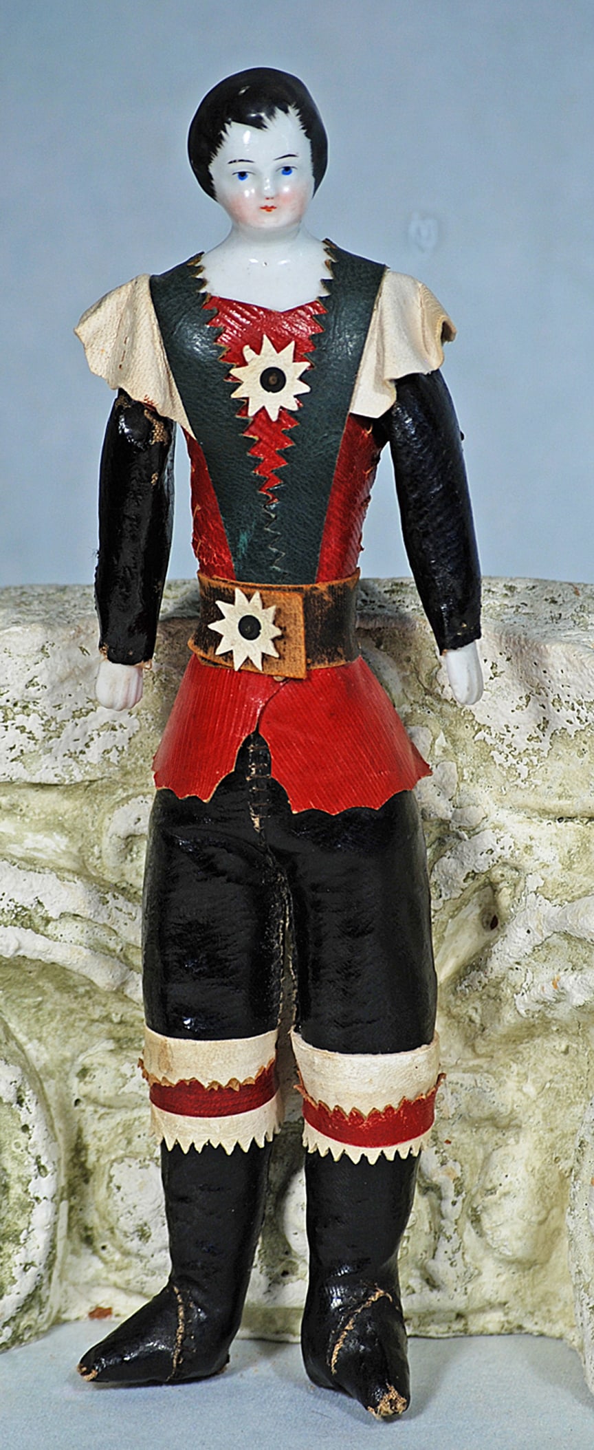 GERMAN PORCELAIN GENTLEMAN IN ALL-ORIGINAL LEATHER COSTUME: 9 ½”. Porcelain Shoulderhead, sculpted black hair with brush-marked detail framing the face, painted features, blue eyes, upper eyeliner, tapered brows, closed mouth, leather body with porc