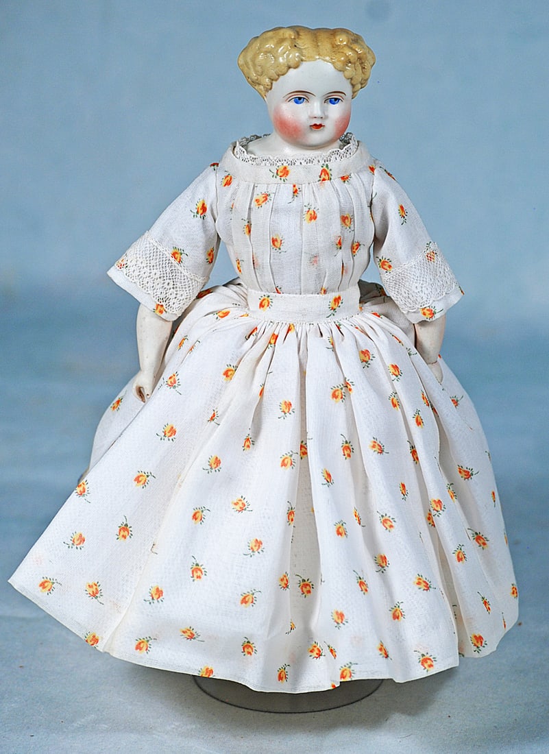 PETITE GERMAN BISQUE LADY WITH BLONDE CURLS: 10 ½”. Bisque shoulderhead, sculpted short blonde hair in tightly sculpted curls from center-part, painted blue eyes, red and black eyeliner, tapered brows, closed mouth, muslin stitch-join