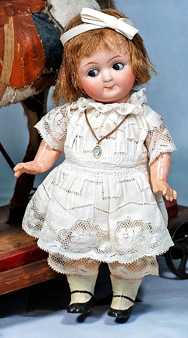 ADORABLE GERMAN BISQUE GOOGLY, 9573, BY GEBRUDER HEUBACH: 9”. Marks 9573 Heubach in square. Bisque socket head, blue side-glancing and sleep eyes, painted lashes, eyeliner, tapered brows, closed mouth, wig, five-piece composition jointed toddler body, 