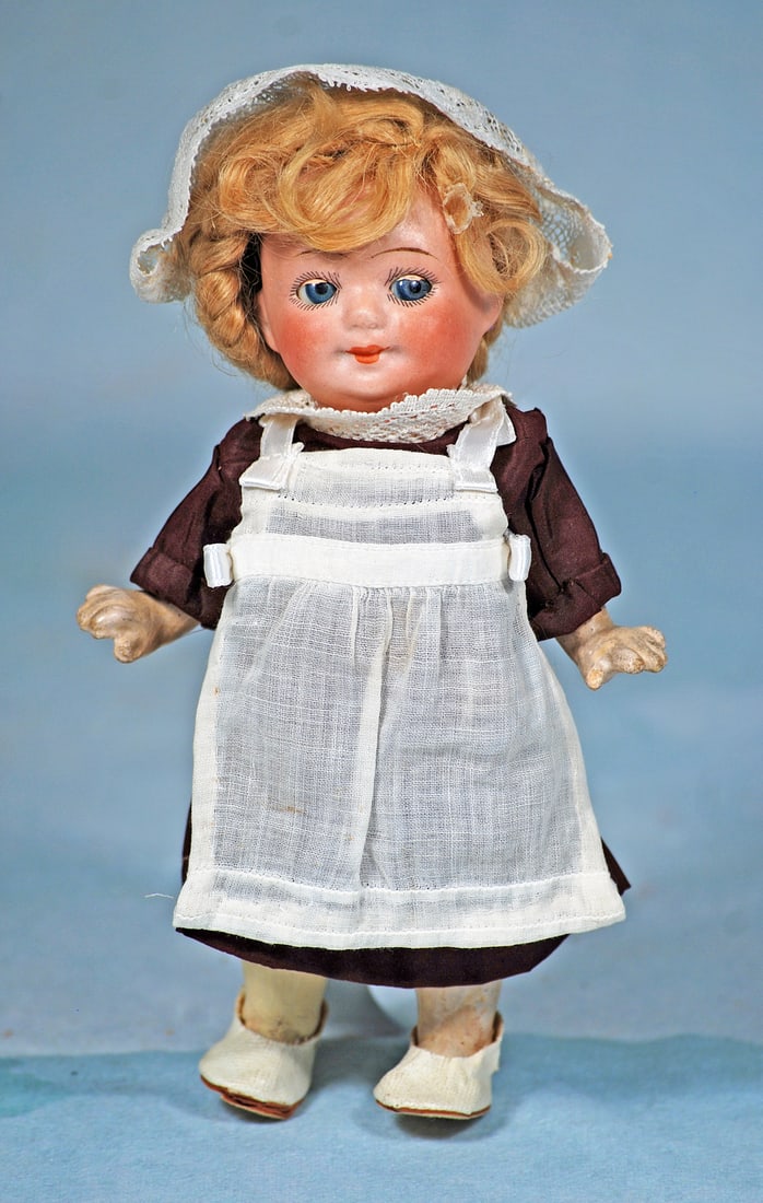 GERMAN BISQUE GOOGLY BY HERM STEINER: 7”. Marks: 133 Germany H S. Bisque socket head, blue googly sleep eyes, painted lashes, tapered brows, closed mouth, original blonde mohair wig, five-piece jointed composition body, cotton dress