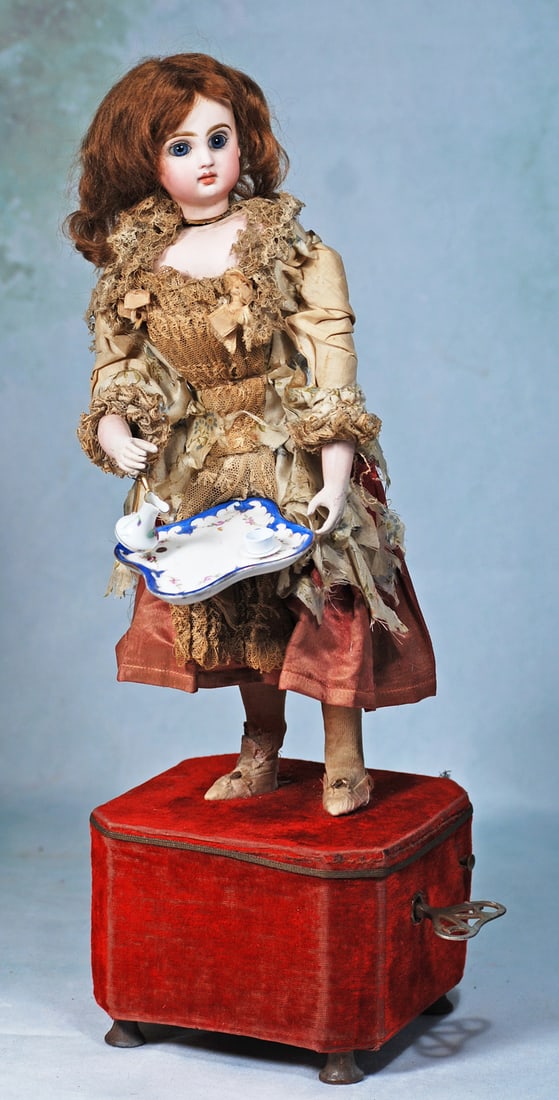 FRENCH BISQUE AUTOMATON “GIRL SERVING TEA” BY GUSTAV VICHY: 19”. Marks: Tete Jumeau Depose 4 (head). Bisque head with blue paperweight eyes, painted lashes, feathered brows, closed mouth, brown mohair wig, bisque shoulderplate, carton torso and legs, wir