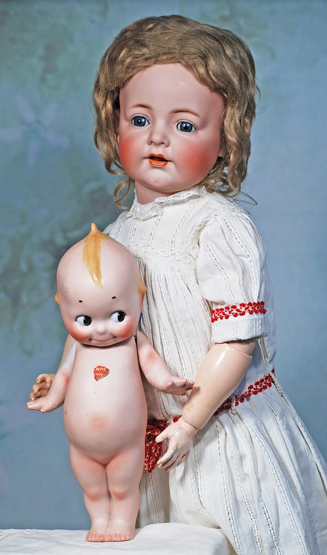 GERMAN BISQUE CHARACTER CHILD, 128, BY KAMMER AND REINHARDT: 24”. Marks: K * R 128. Bisque socket head, blue sleep eyes, painted lashes, feathered brows, dimpled cheeks, open mouth, accented lips, upper teeth, antique light brown mohair wig, composition a