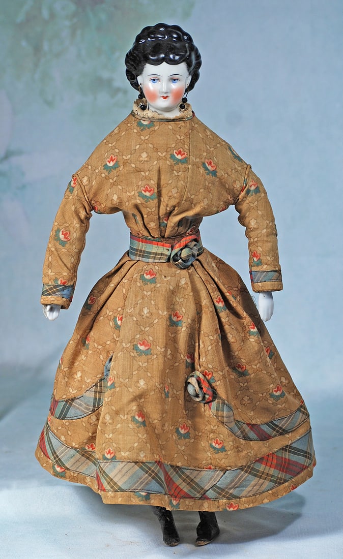 GERMAN PORCELAIN LADY WITH ELABORATE COIFFURE AND PIERCED EARS: 17”. Porcelain shoulderhead, sculpted black hair in elaborate arrangement of curls drawn to the back behind partially modeled pierced ears, stippling detail at the sides, painted features, light