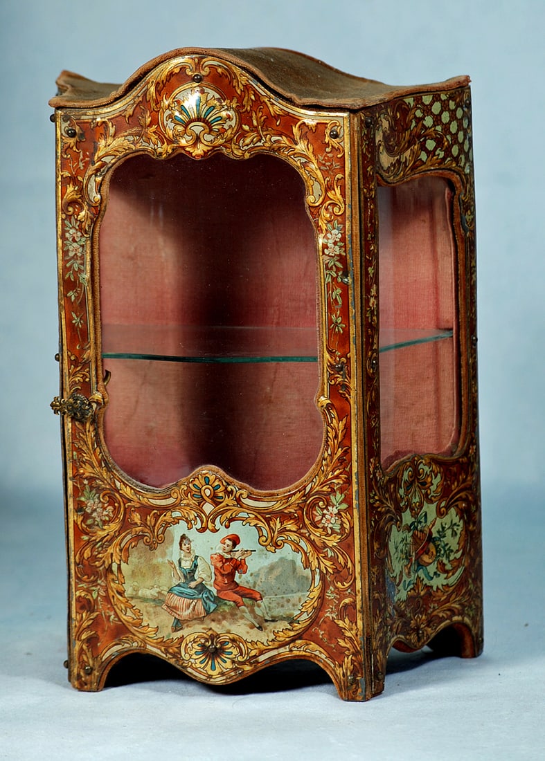 FRENCH MINIATURE VITRINE WITH WONDERFUL DECORATIONS: 10”. Wooden frame vitrine that is covered with decorative finish, gracefully shaped glass front and sides, extensive lithographed details of French scenes with scroll work, lattice and garlands,