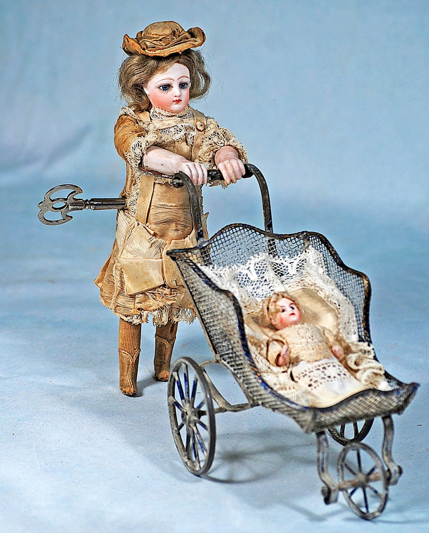 FRENCH MECHANICAL TOY “LITTLE GIRL WALKING HER DOLL”: 12 x 8”. A bisque head doll with blue paperweight eyes, painted lashes, feathered brows, closed mouth, carton torso, wooden legs, bisque forearms. Original mohair wig and original silk dress,