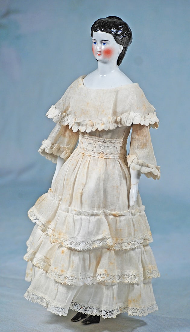 PETITE GERMAN PORCELAIN LADY WITH LONG SIDE CURLS: 13”. Porcelain shoulderhead, heart-shaped face with sculpted black hair waved to the sides from center part, drawn behind the ears with long side curls falling onto her shoulders, pulled up high