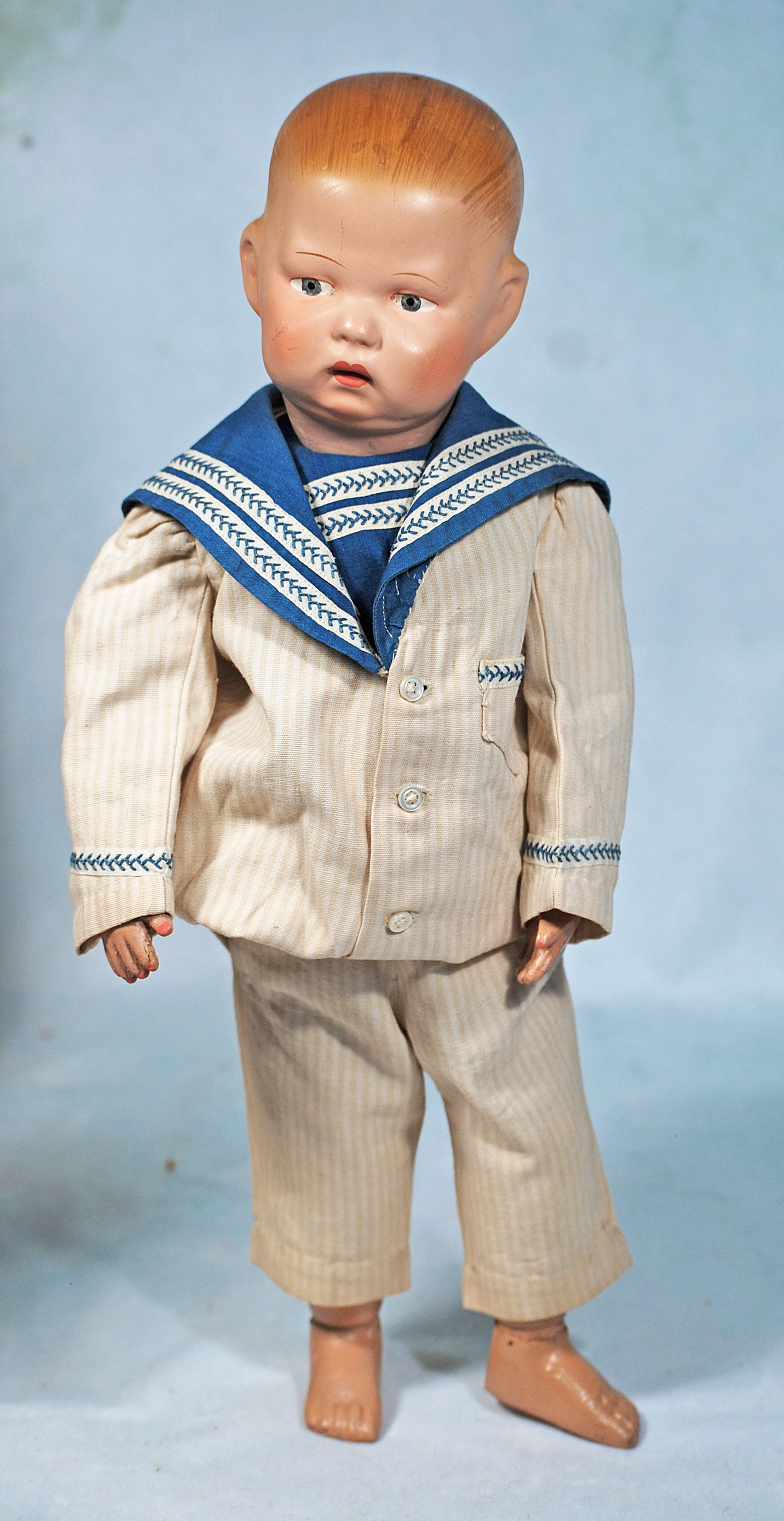SCHOENHUT WOODEN BOY WITH POUTY FACE: 16 ½”. Marks: Schoenhut label on back of torso. Carved wooden socket head, spring-jointed wooden body, painted blonde hair, blue eyes, upper eyeliner, single-stroke brows, closed mouth, two